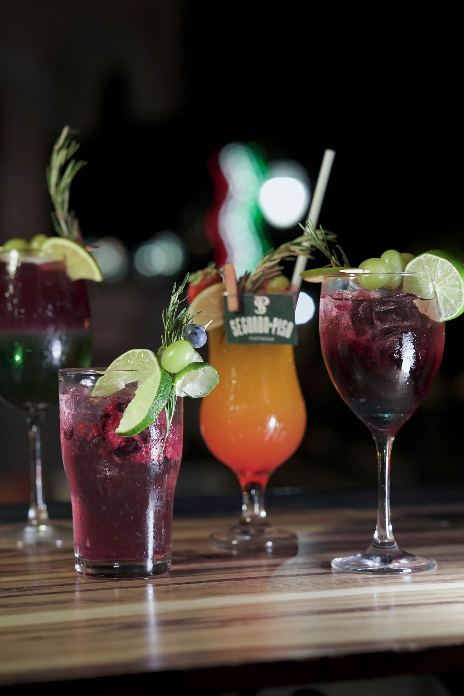 Colorful cocktails with fresh garnishes on a wooden surface, perfect for social gatherings.