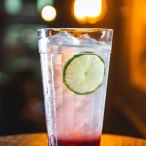 Cool cocktail with a lime slice, ice, and vibrant lighting in a bar setting.